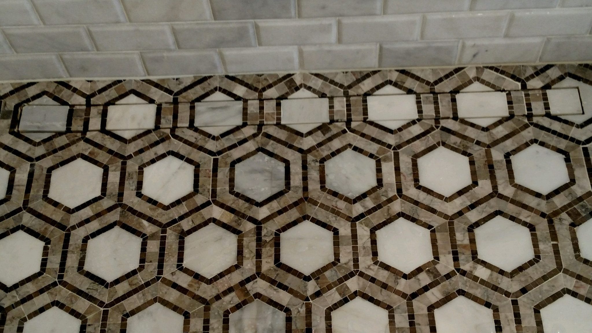 Linear shower drain hidden in the hexagonal bathroom tile flooring