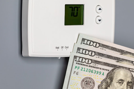 A thermostat is pictured with money.