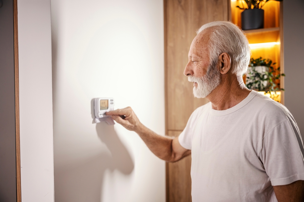 a senior man, confused, as he tries to get his heat pump to switch from heating to cooling by using the thermostat
