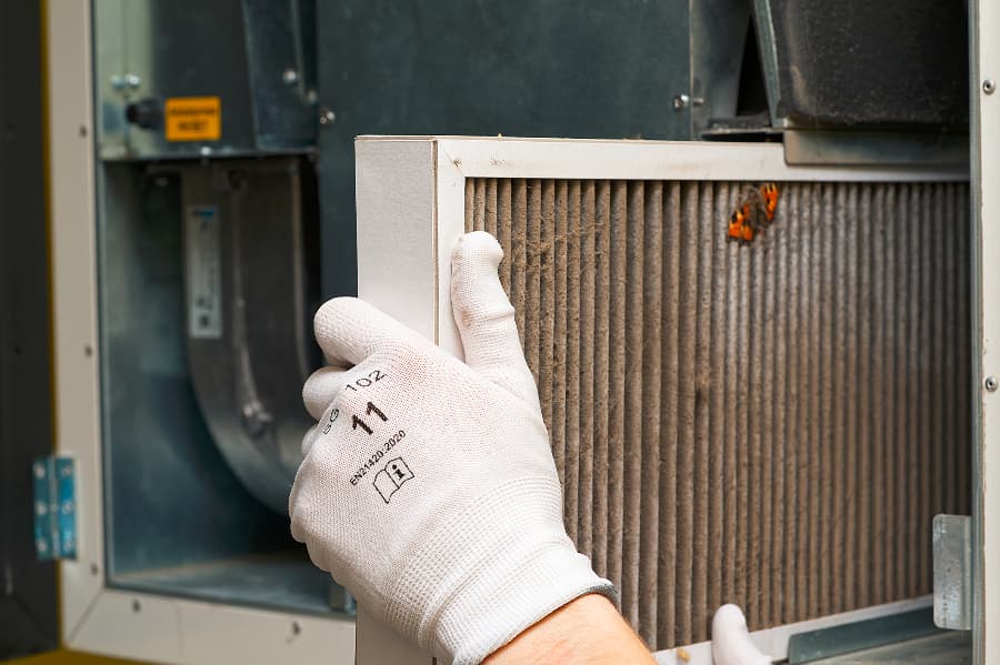 Technician replacing HVAC filter in central ventilation system